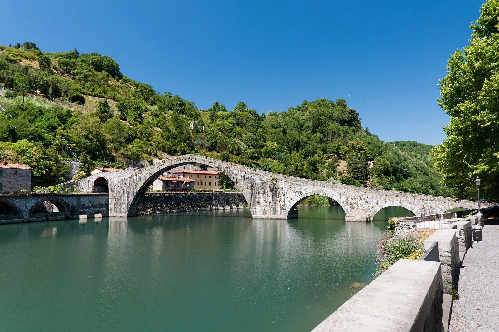Il medievale Ponte del Diavolo a schiena d'asino che si riflette nel fiume Serchio a Borgo a Mozzano